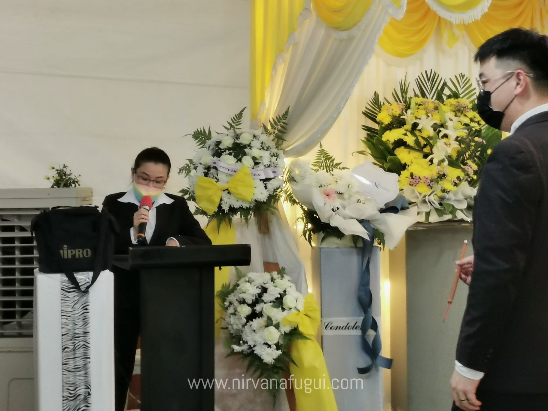 A female funeral director from Nirvana Singapore on an emcee role at a client's Buddhist funeral wake